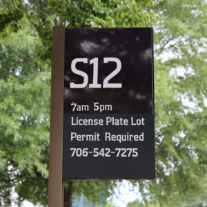 Parking lot sign for campus lot S12. 7am-5pm, License Plate Lot, Permit Required, 706-542-7275